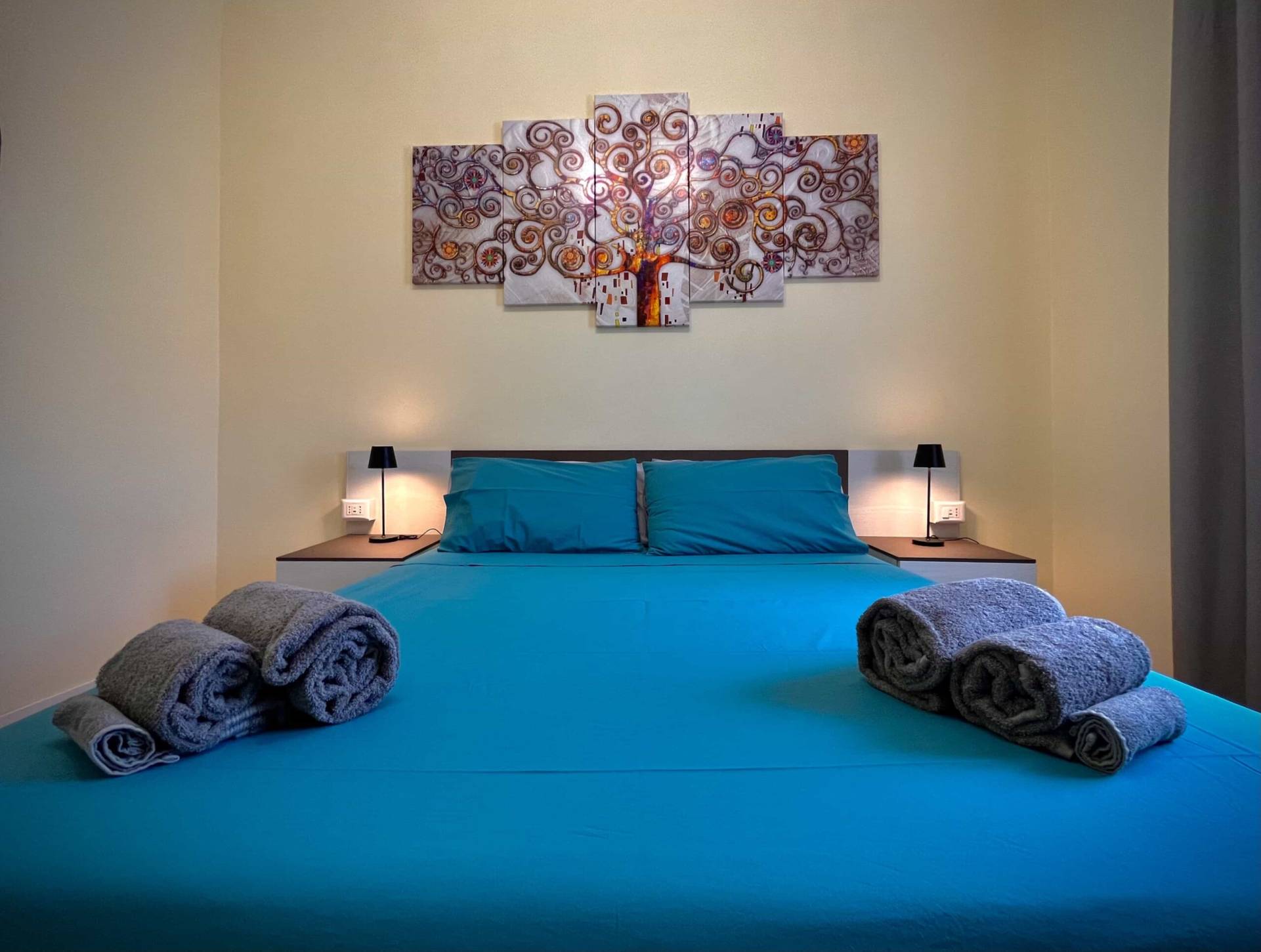 Cozy Bed with Stylish Artwork Above, Comfortable Mattress, and Night Lamps at Furnished Nettuno Solarium Apartment